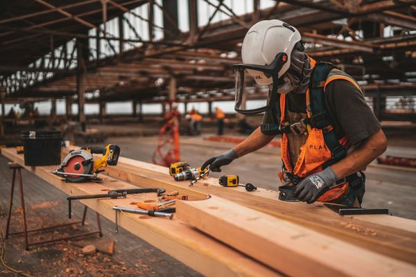 A builder in safety gear cutting timber on site
