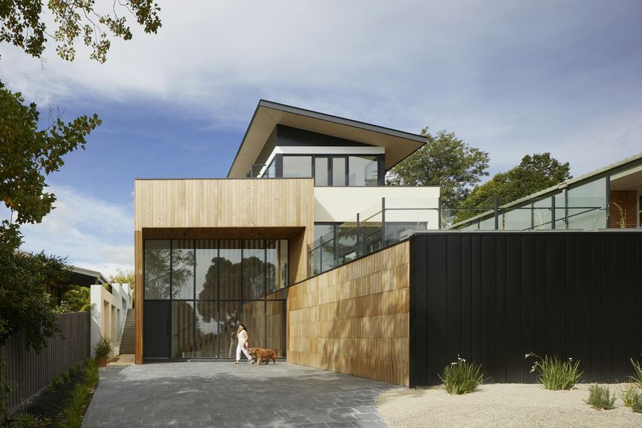 A timber and black-clad modern home with a gravel drive