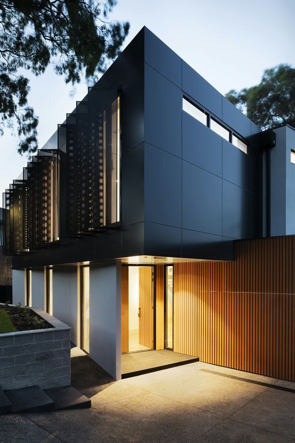 A dark-clad modern house lit at dusk