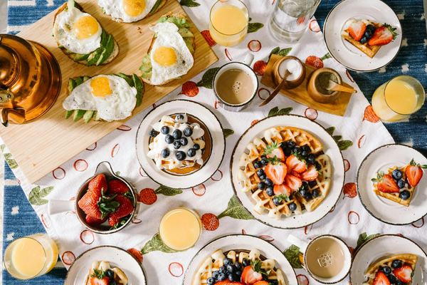 A table spread with waffles, eggs, fruit and juice