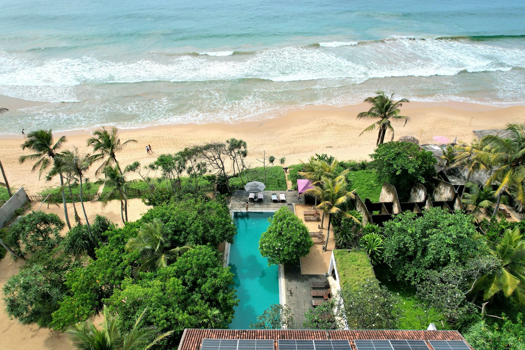 The house from above: pool and terraces held between dense jungle and a surf beach.